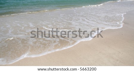 Surf running up on white sandy beach, background