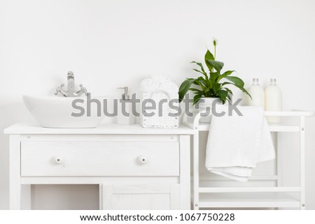 Compact bathroom interior with white vintage furniture, shelf, towels and sink
