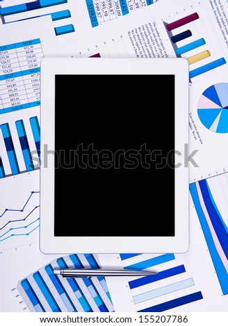 Touchpad above financial paper charts and graphs on the table