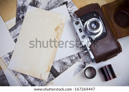 Composition of retro camera with film strip and old photographs