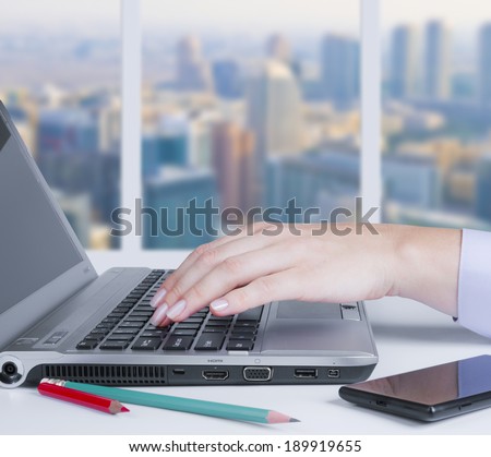 Typing on keyboard at the office desk on city background