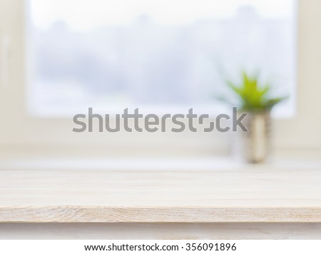 Wooden table on defocuced winter window background