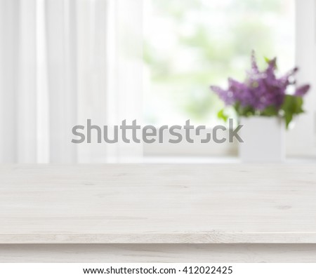 Wooden table on defocused window with purple flower pot background