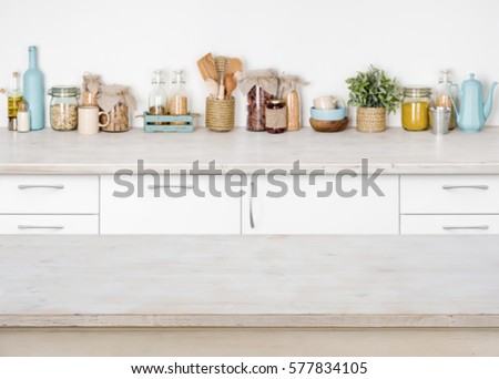 Empty wooden kitchen table on blurred background of food ingredients.