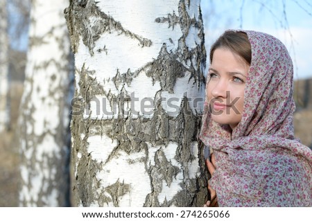 Russian girl in a scarf in a birch forest close up