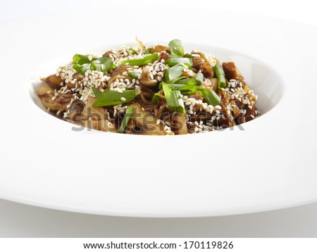 Bowl of stir fried udon noodles with mushrooms garnished with sesame seeds