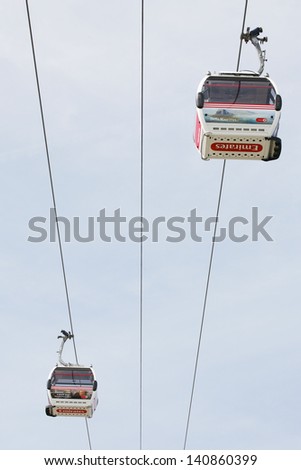 LONDON - MAY 26: Gondolas of the Emirates Air Line cable car, opened June 2012, run by TFL, links the Greenwich Peninsula with Royal Dock, 1km, across the River Thames on 26 May, 2013.