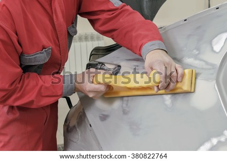Car painter prepares the rear wing of the car for painting.