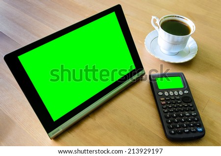 workplace with tablet pc - green box, calculator and cup of coffee - stock photo
