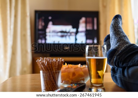 Television, TV watching (movie) with feet on table and huge amounts of snacks - stock photo