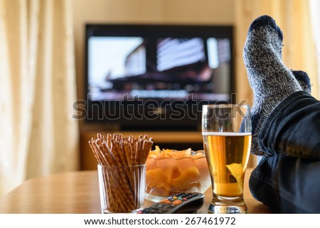Television, TV watching (movie) with feet on table and huge amounts of snacks - stock photo