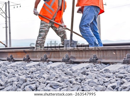 railway embankment, rails and workers in orange vests