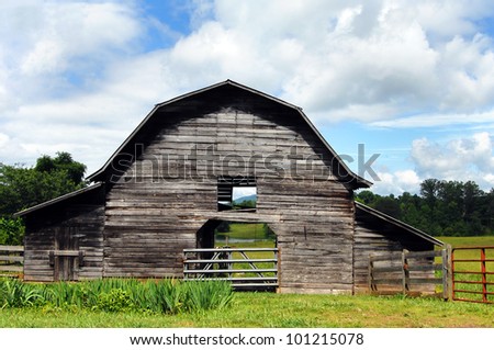 Beautiful landscape photo of weathered, wooden barn in Clay County, Virginia.  Open breeze way through barn shows pond, cows and mountain in opening.