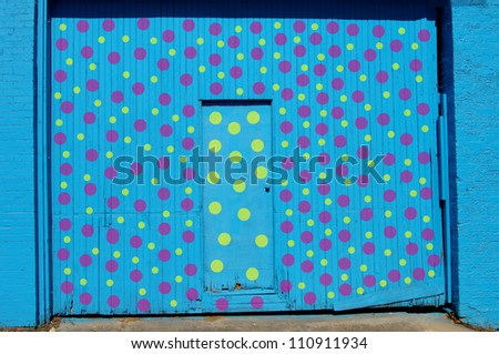 Wall and double door has been painted brilliant blue.  Yellow and purple polka dots decorate surface.