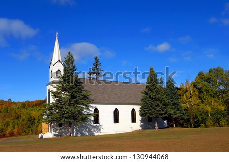 Phoenix Church, also known as the Church of the Assumption, sits amid the Fall colors of Upper Peninsula, Michigan.  Wooden architecture is complete with steeple and cross.