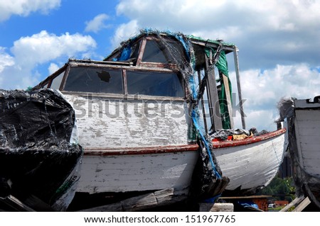 Ruins of old fishing boat sits near Lake Superior in Ripley, Upper Peninsula, Michigan.  Wooden boat has cracked and peeling paint, broken window and is covered with tarps.