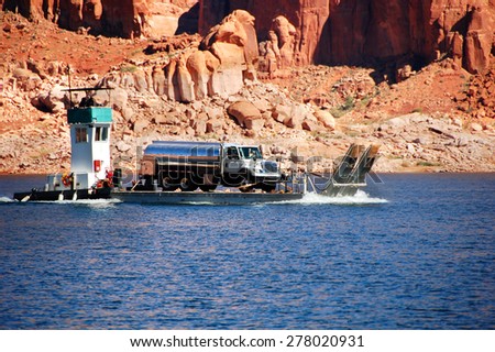 Tugboat transports barge loaded with a tanker truck on Lake Powell in Arizona.