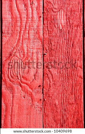 Rough textured red painted wooden boards.  Sunshine makes red vibrant.