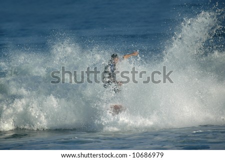 Man seems to walk on water as he wipes out in rough wave.  Water splashing and flying droplets fill screen.