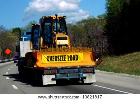 Oversize load of bulldozer is loaded on a flatbed trailer being pulled by a semi.  Travel is by interstate.