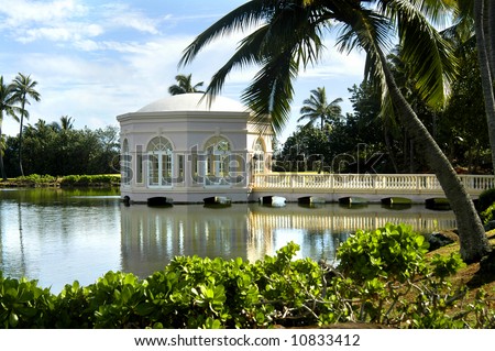 Chapel of Love on the Island of Kauai.  Reflection in still waters of lagoon.  Blue skies and leaning palm tree.