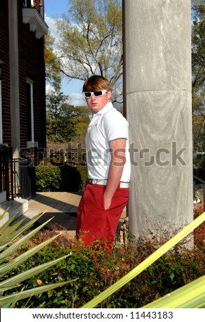 Cool shades for a hot day.  Male teen leans back against a column on the steps of building.