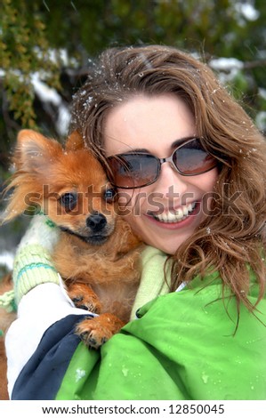 Beautiful young woman poses with her best friend, a pomeranian dog.  Green jacket and sunglasses.
