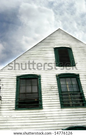 Aging country store has white wooden clapboard front trimmed in green wood framed windows.