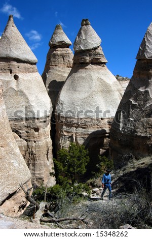 Fascinating Tent Rocks in New Mexico has pyramid shaped domes carved by erosion from wind and rain.  Man hikes trail.