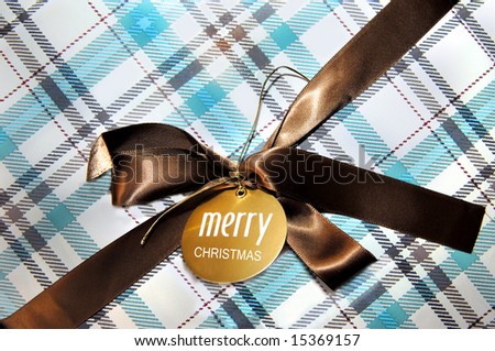 Box is wrapped in aqua and brown retro colored Christmas paper.  Brown ribbon with bow has tag that reads \