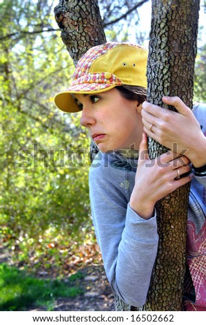 Fear is not a laughing matter, but sometimes it is better to laugh than cry.  Female teen is wedged in branches of tree and waring yellow hat.