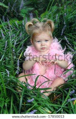 Boa feathers decorate this little girl as she plays princess in a garden.