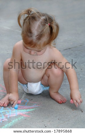 Toddler draws on sidewalk with sidewalk chalk creating her own masterpiece.