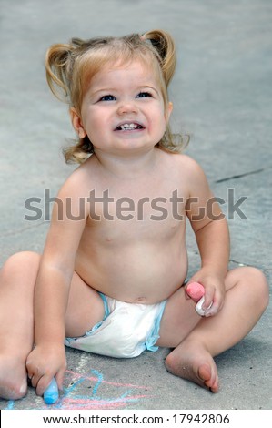 Baby draws on pavement with colorful chalk.  She has it all over her mouth and hands.