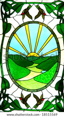 Stained glass door has valley in green and a sunrise of yellow.  Birds and leaves decorate outside edges.