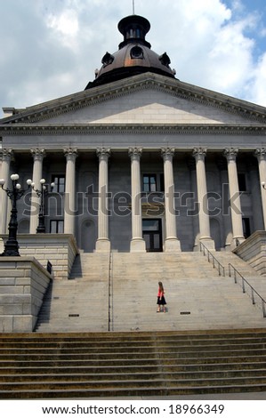 Young woman stands on the steps of the capital of South Carolina in Columbia.  She is looking back at the building.