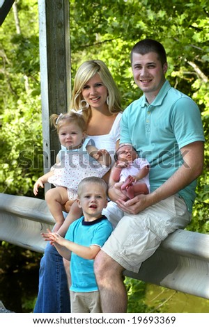 Family of five enjoy a day outdoors.  Sunny with green foliage in background.