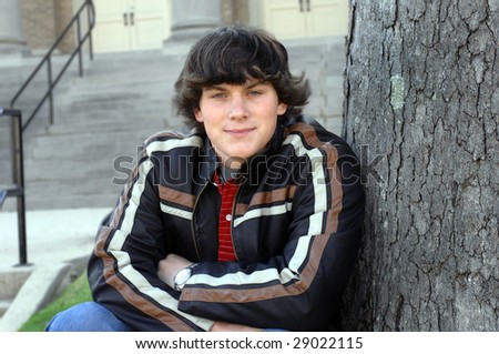 Arms resting on knees, teen sits in front of dorm steps.  Leather jacket.