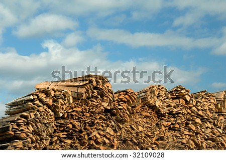 Large stock pile of wooden shakes ready for shipping fill wood yard.  Blue sky and clouds.