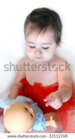 Baby touches her doll and shares her sadness.  Child is dressed in red net skirt and has tears running down her cheeks.