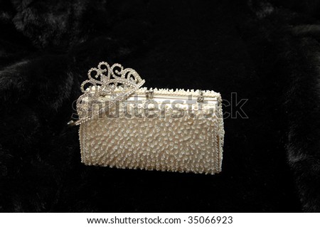 purse supports a rhinestone tiara Black fur serves as background
