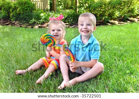 stock-photo-two-children-sit-on-grass-enjoying-a-big-lollipop-in-rainbow-colors-both-have-it-smeared-around-35722501.jpg
