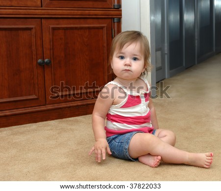 Baby pauses as she faces her fears of the dark hallway in her home.  Denim shorts and summer top with bare pink painted toenails.