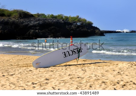 Life guard surf board sits ready for action.  The word Rescue is painted in black on the board.