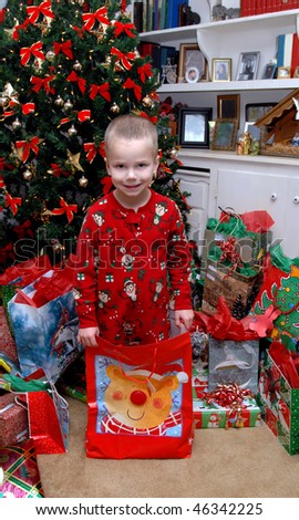 The best gifts come in small packages.  Little boy stands in gift bag on Christmas morning as a surprise for someone special.