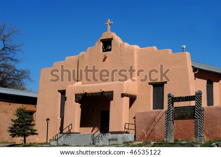 Aging Saint Anthony Church in Dexon, New Mexico has bell tower and crumbling cross steeple.  Stucco building with wooden sign.