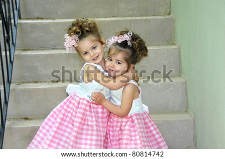 Two sisters dressed identically embrace on Easter Sunday morning.  They are both smiling and happy.