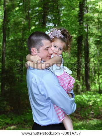 Father and daughter share a tender moment.  Her arms are wrapped around her father\'s neck hugging him tightly.  Dad\'s eyes are closed treasuring the moment.