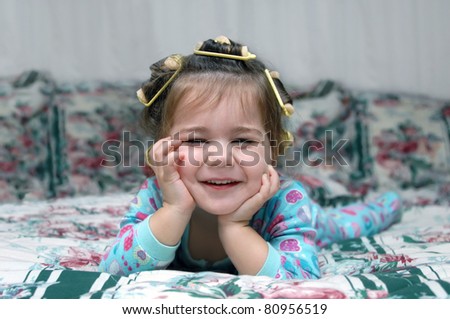 Toddler is ready for bed including pajamas and sponge hair rollers.  She is smiling and laughing enjoying her beauty treatment.