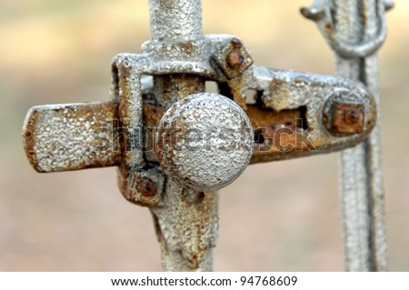 Antique, silver painted, iron gate has round knob and metal bar.  Exposed to the elements handle has rust and metal is degrading.